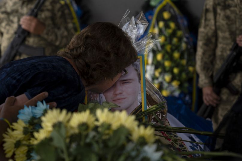 Zynaida Nedoleshko embrasse la photo de son neveu, Roman Shadlovskyi, lors d'un service de réinhumation pour lui à Bucha, juillet 2023