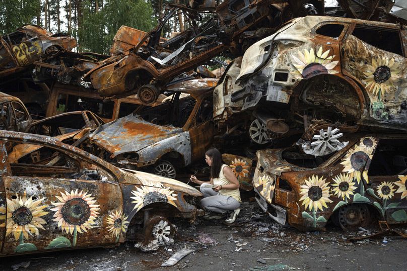 L'artiste ukrainienne Olena Yanko peint des tournesols sur des voitures détruites par les attaques russes à Irpin, en août 2022.