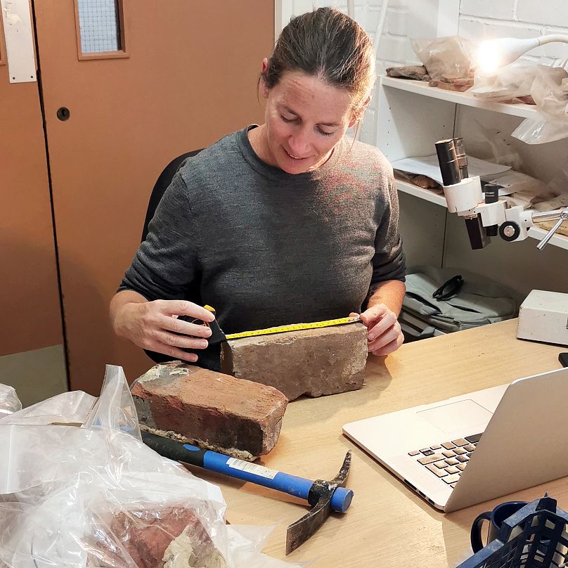 Rae Regensberg, spécialiste des matériaux de construction en céramique à Archéologie Sud-Est, examine les briques du site de fouilles.