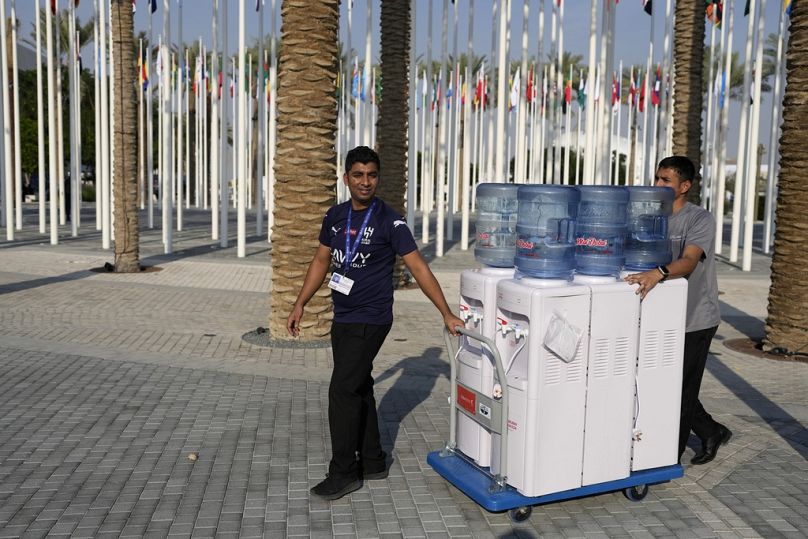 Les travailleurs déplacent des carafes d'eau alors que le Sommet des Nations Unies sur le climat COP28 touche à sa fin à Dubaï, en décembre 2023.