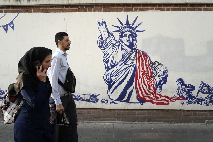 Des gens passent devant une fresque anti-américaine peinte sur le mur de l'ancienne ambassade américaine à Téhéran, août 2023.