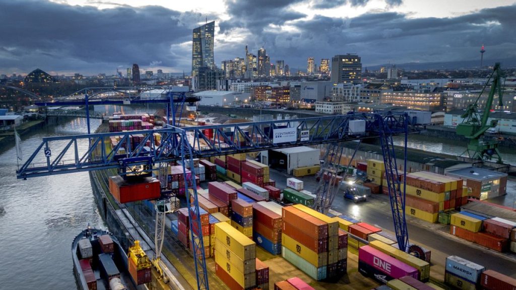 A container is loaded onto a cargo ship in the harbor in Frankfurt, Germany, Wednesday, Dec. 13, 2023. In background the European Central Bank. (AP Photo/Michael Probst)