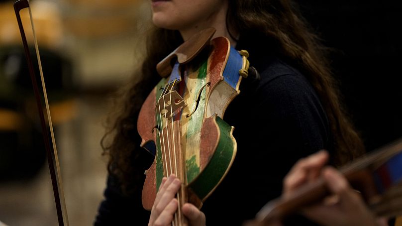 Une femme membre du « Sea Orchestra » répète avec un violon fabriqué à partir du bois de bateaux d'immigrants naufragés à Milan, dans le nord de l'Italie, le samedi 10 février 2024.