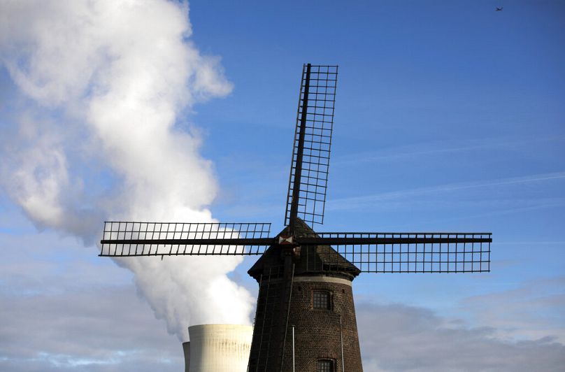 De la vapeur s'élève d'une centrale nucléaire derrière un vieux moulin à vent sur l'Escaut à Doel, septembre 2019