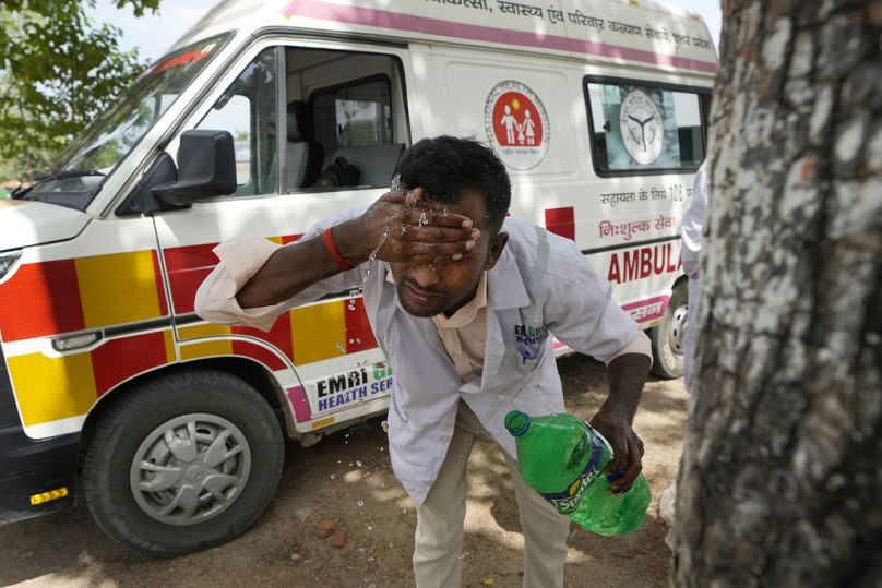 Un ambulancier se lave le visage avec de l'eau pour se rafraîchir après avoir déposé un patient à l'hôpital du district de Lalitpur, à Banpur, juin 2023.