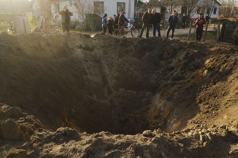 Des gens regardent le cratère d'une explosion dans un village de Horodnya, région de Tchernihiv, avril 2022.