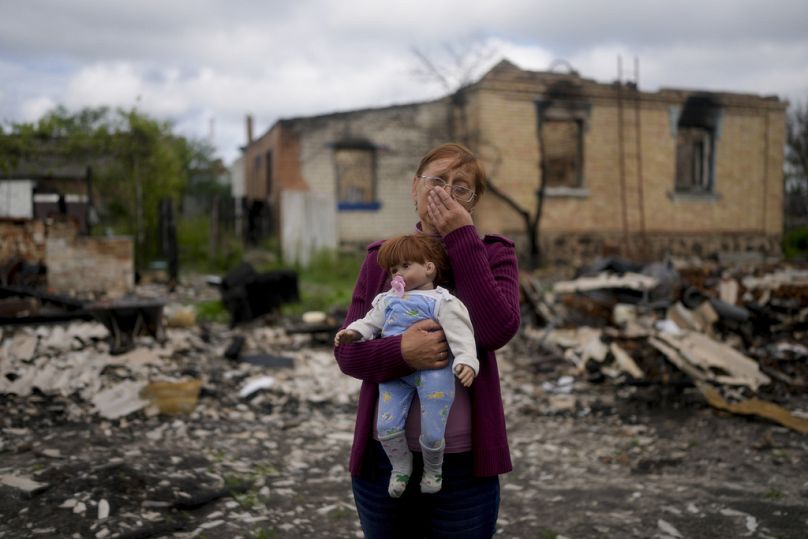 Nila Zelinska tient une poupée appartenant à sa petite-fille qu'elle a trouvée dans sa maison détruite à Potashnya, dans la banlieue de Kiev, mai 2022