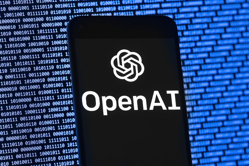 Le logo OpenAI apparaît sur un téléphone portable devant un écran d'ordinateur avec des données binaires aléatoires, jeudi 9 mars 2023