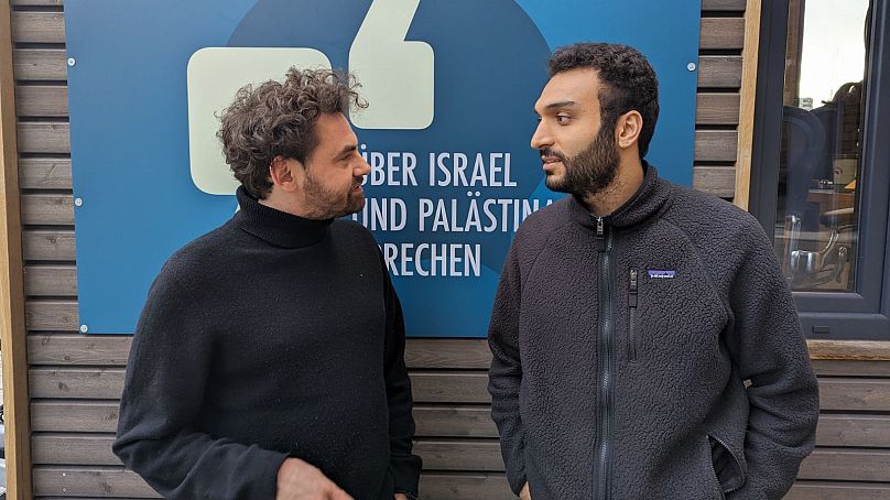 Shai Hoffmann (à gauche) discutant avec Ahmad Dakhnous (à droite) devant Tiny Space sur la Potsdamer Platz, Berlin