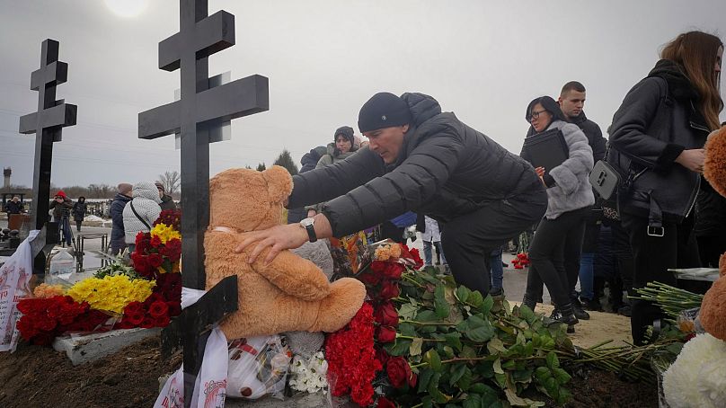 Des gens déposent des jouets et des fleurs sur les tombes d'une famille tuée dans un incendie lorsqu'un drone russe a frappé leur maison dans un quartier résidentiel de Kharkiv, en Ukraine, le 12 février 2024.