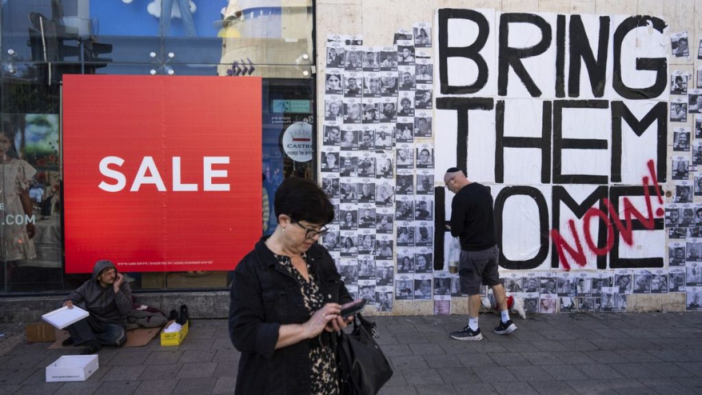 People walk past a wall with photographs of hostages, mostly Israeli civilians who were abducted during the Oct. 7, unprecedented Hamas attack on Israel, in Tel Aviv, Israel.