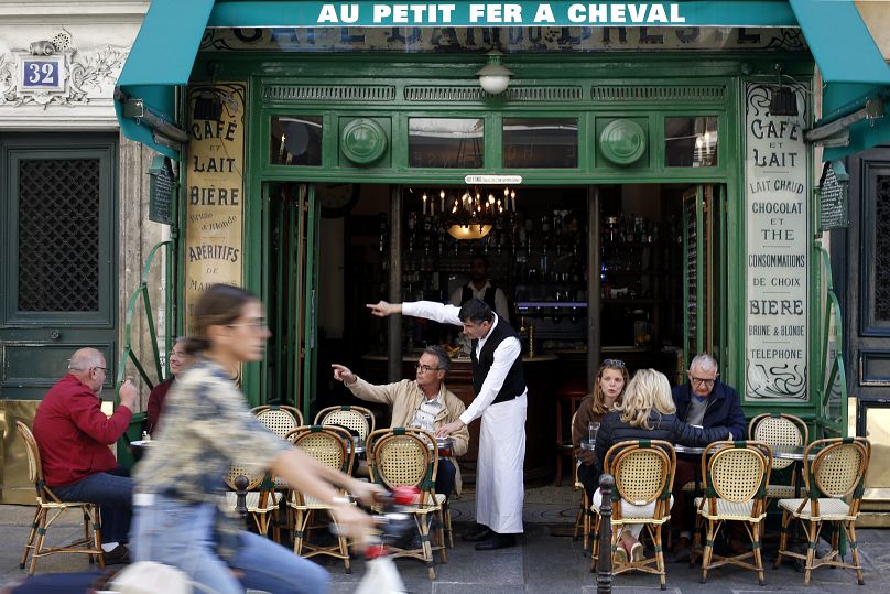 Le serveur Didier Hubert, au centre, indique la direction à un client du café 