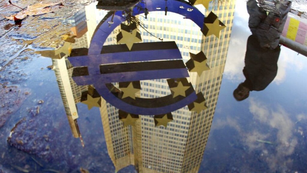 In this Thursday, Jan. 5, 2012 file photo, a person is reflected in a puddle alongside the Euro sculpture in front of the European Central Bank in Frankfurt, Germany.