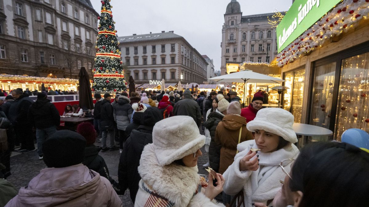 Visitors eat Chimney Cake, a traditional Hungarian festive food at one of Europe