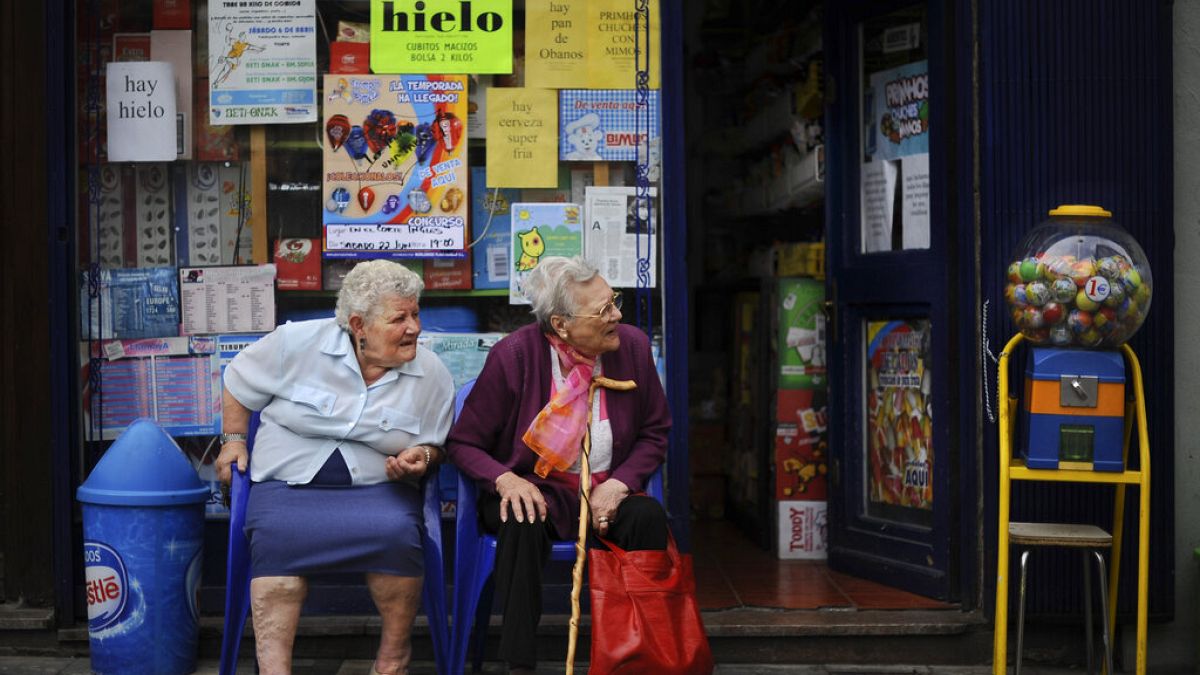 Two elderly women enjoy the day while they rest outside a shop, in Pamplona, northern Spain on Monday, June 17, 2013.