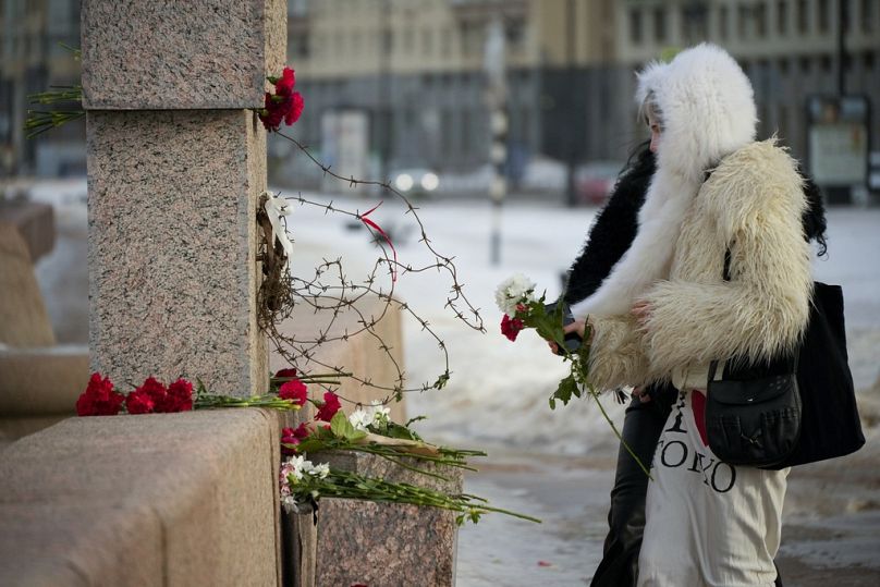 Des femmes déposent des fleurs au Mémorial aux victimes de la répression politique pour rendre hommage à Alexei Navalny à Saint-Pétersbourg, en Russie, le mardi 20 février 2024.