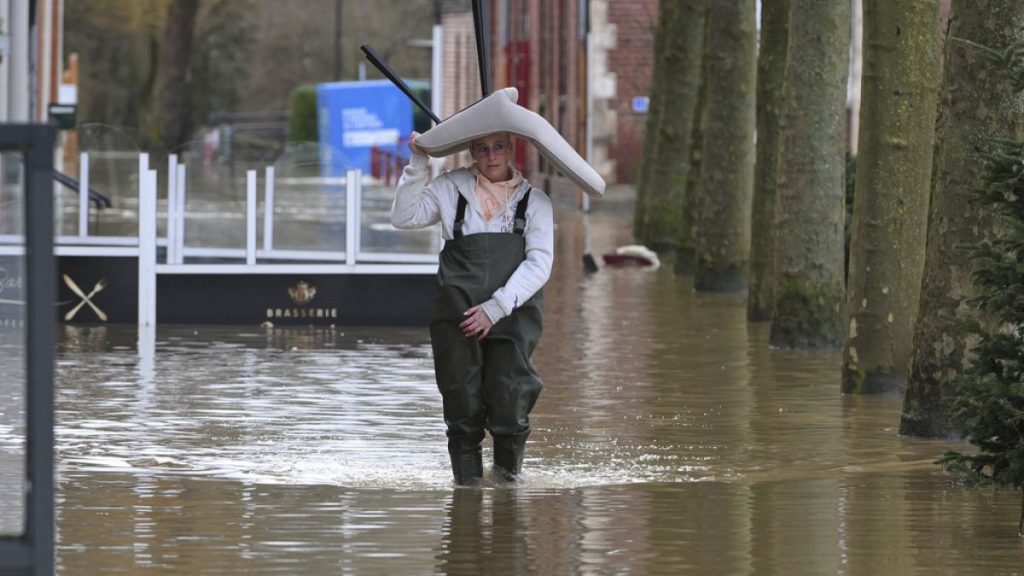 A woman carries a chair on her head as she walks in a flooded street of Arques, northern France, Thursday, Jan.4, 2024.