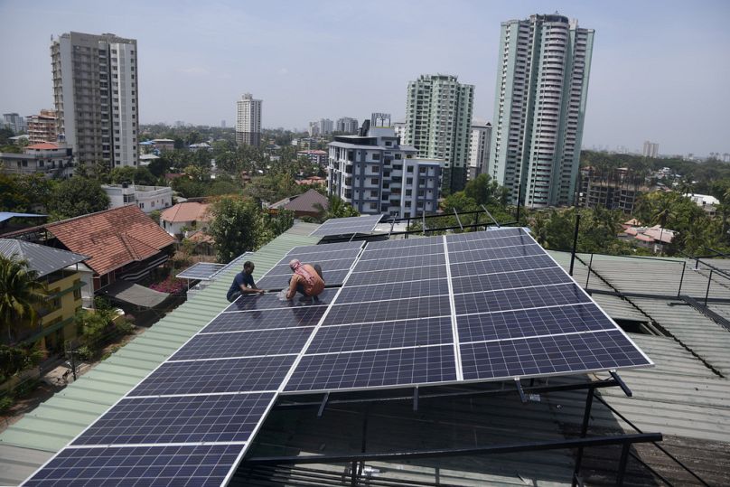 Des ouvriers installent des panneaux solaires sur le toit d'un appartement résidentiel à Kochi, dans l'État du sud du Kerala, en Inde.