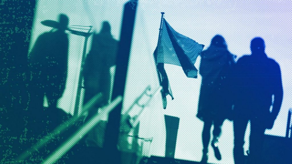 A couple walk past EU flags outside EU headquarters in Brussels, October 2021