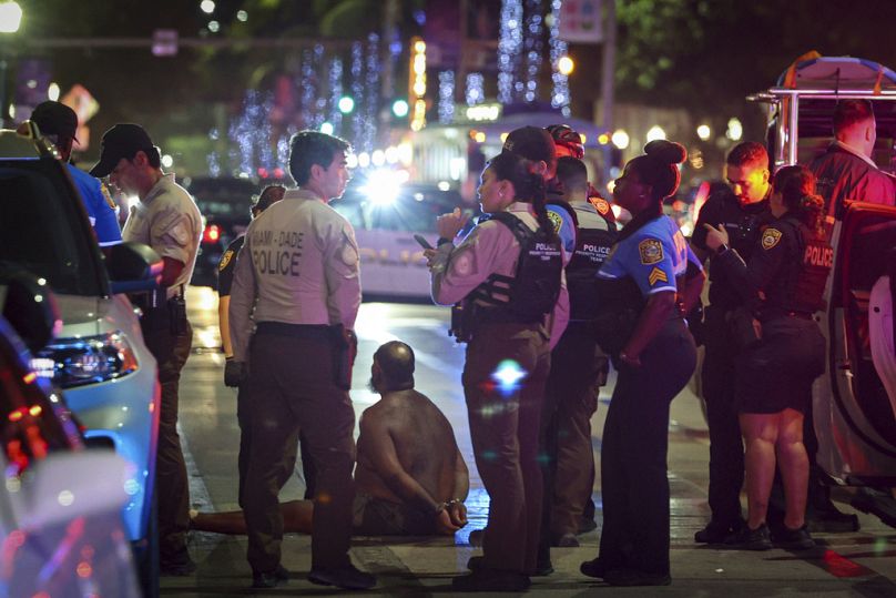 Un homme est assis par terre, menotté après que des témoins ont déclaré qu'il semblait brandir un couteau à Miami Beach en mars dernier.