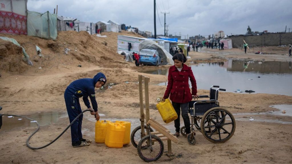 Palestinians displaced by the Israeli air and ground offensive on the Gaza Strip gather water in a makeshift tent camp in Rafah on the border with Egypt, 27 January 2024.