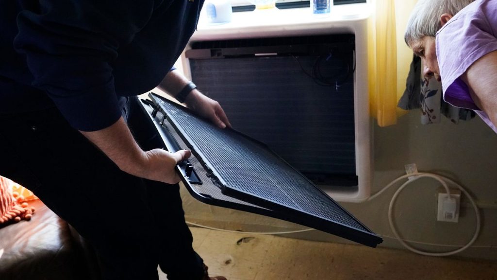 Regina Fred touches one of her window-mounted heat pumps in her apartment in the Queens borough of New York.