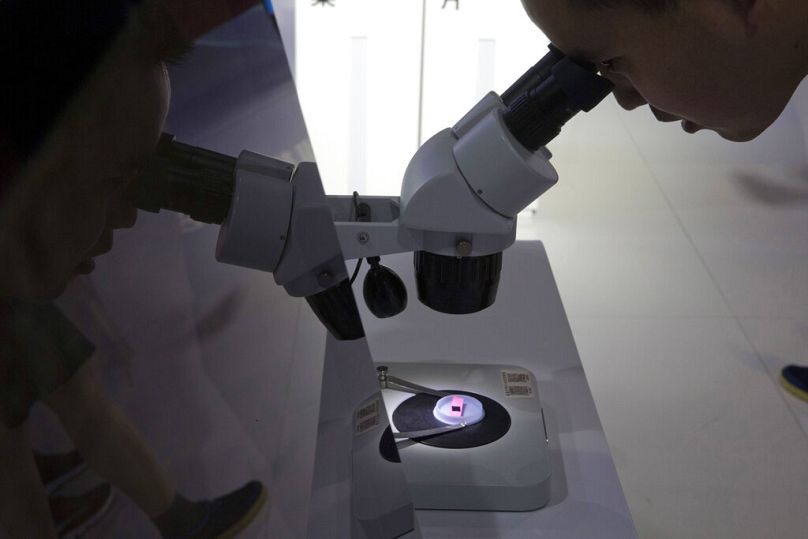 Un visiteur de la 21e Exposition internationale de haute technologie de Pékin en Chine examine une puce informatique au microscope, à Pékin, en mai 2018.