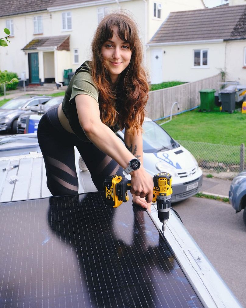 Jessica installe un panneau solaire de 400 W sur le toit de la camionnette.  Malgré la conduite, le couple a réduit son empreinte carbone d'un tiers.