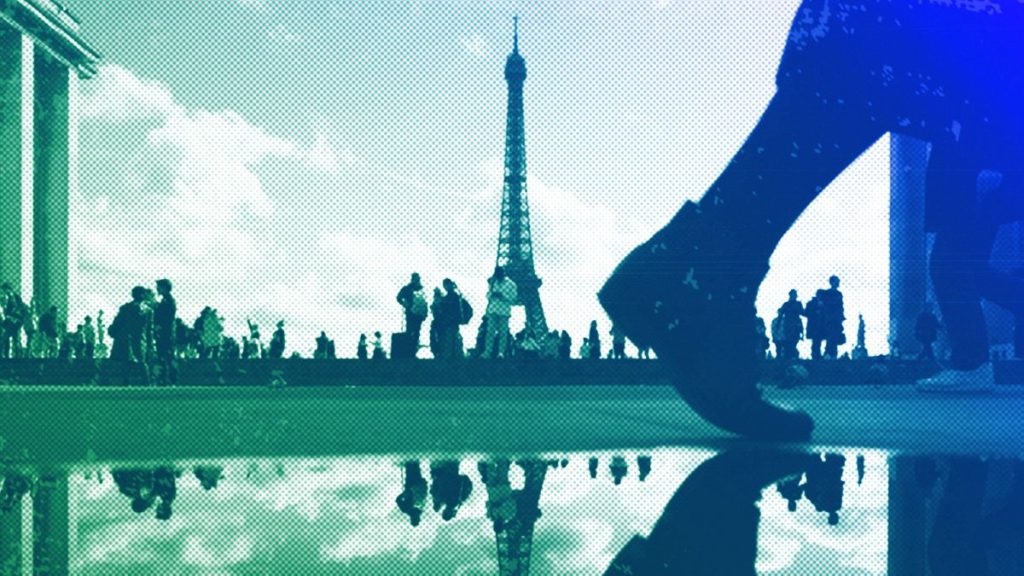 The Eiffel Tower is reflected in a puddle as people walk past at the Trocadero square, in Paris, October 2023