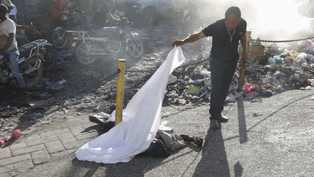 A person lifts a sheet to look at the identity of a body lying on the ground after an overnight shooting in the Petion Ville neighborhood of Port-au-Prince, Haiti, 18/3/24.