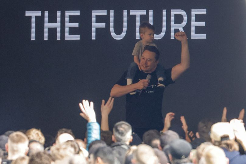 Le PDG de Tesla, Elon Musk, entre sur scène avec un enfant sur les épaules à la Tesla Gigafactory pour voitures électriques à Gruenheide, près de Berlin, en mars 2024.