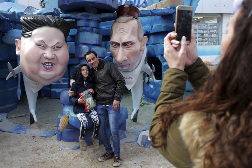 Les gens prennent des photos à côté des statues du dirigeant nord-coréen Kim Jong Un, à gauche, et du président russe Vladimir Poutine en tant que requins lors des célébrations du carnaval à Torres Vedras.