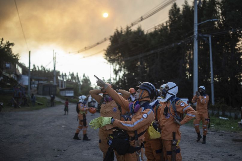 Des secouristes pointent du doigt un incendie qui brûle sur les pentes des montagnes entourant Nemocon, au nord de Bogota, janvier 2024.