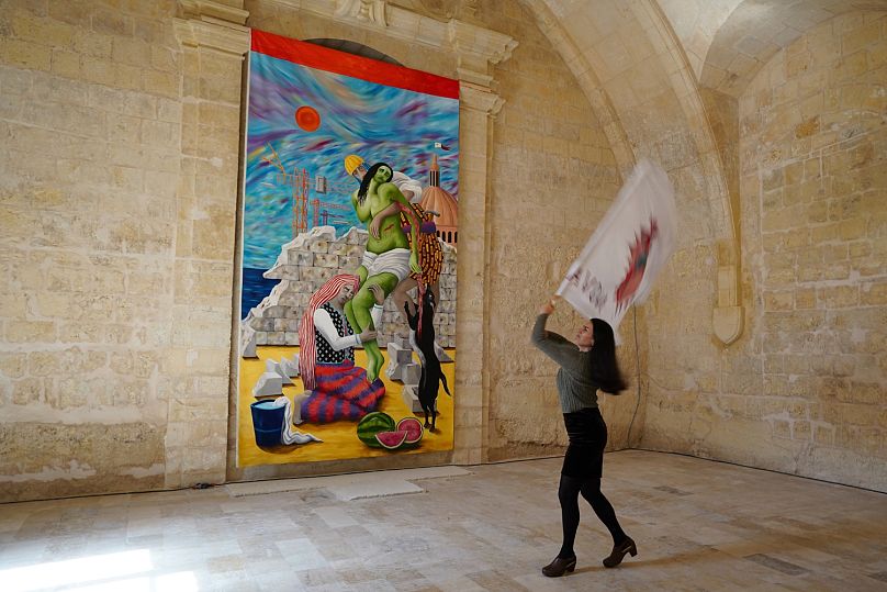 L'artiste italienne Teresa Antignani agite un drapeau devant sa peinture à l'huile « Depozione (Déposition) ».  Elle a ajouté les pastèques comme symbole de la résistance palestinienne, a-t-elle déclaré.