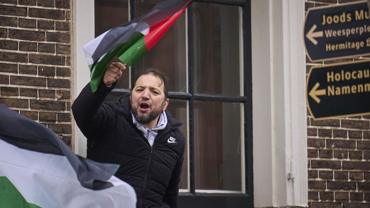 A man waves a Palestinian flag next to signs for the Holocaust Monument and the Jewish Museum as demonstrators protested against Israel