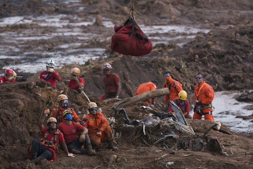 Les pompiers observent le corps d'une personne qu'ils ont retirée de la boue, alors qu'il est soulevé et emmené par un hélicoptère quelques jours après l'effondrement d'un barrage à Brumadinho, janvier 2019.