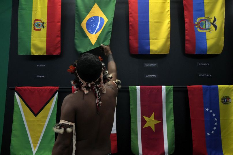 Un indigène passe la main sur le drapeau brésilien lors des réunions du Dialogue Amazonien au centre des congrès Hangar de Belém, en août 2023.