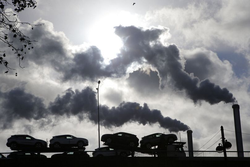 de la fumée s'élève d'une usine alors qu'un camion chargé de voitures traverse un pont à Paris, novembre 2018