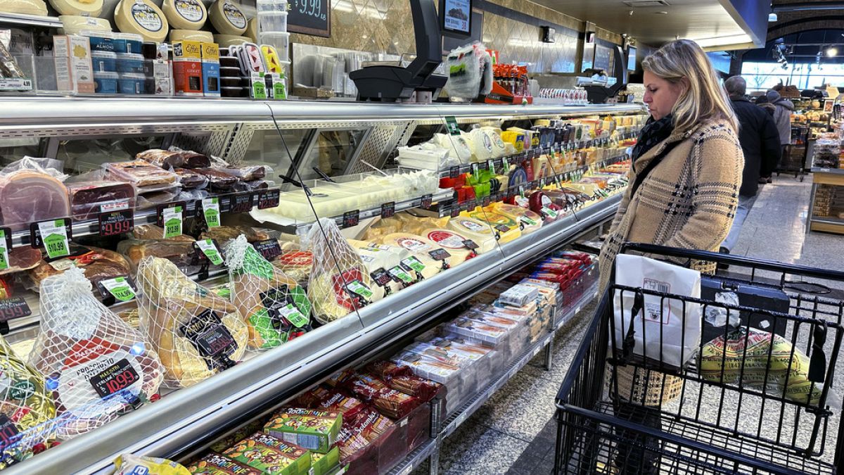 A woman checks prices as she shops at a grocery store in Wheeling, Ill., Friday, Jan. 19, 2024.