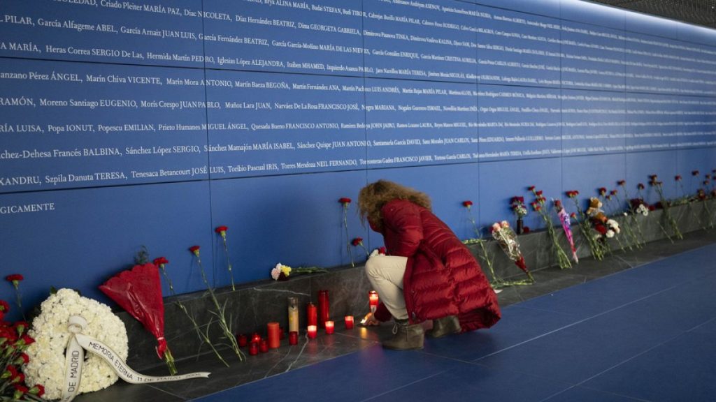 A woman lights a candle at a memorial to the victims of the train bombing inside the Atocha train station in Madrid, Spain, Monday, March 11, 2024.