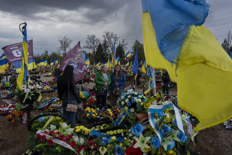 Amis et parents visitent la tombe d'un militaire ukrainien au cimetière de Kryvyi Rih, dans l'est de l'Ukraine, le dimanche 23 avril 2023.