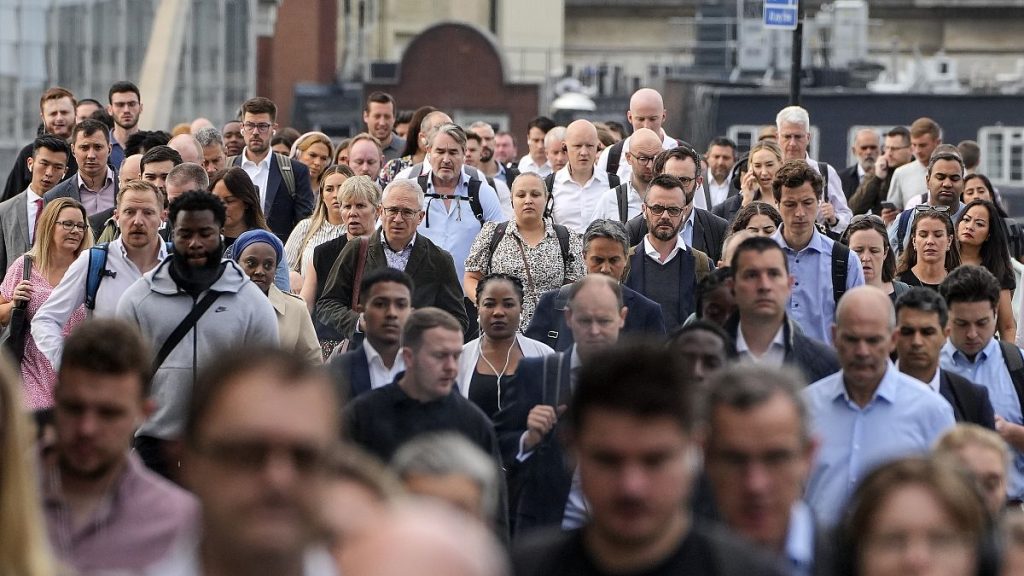 People walk over the London Bridge to work in the City of London on Monday morning, Sept. 12, 2022.