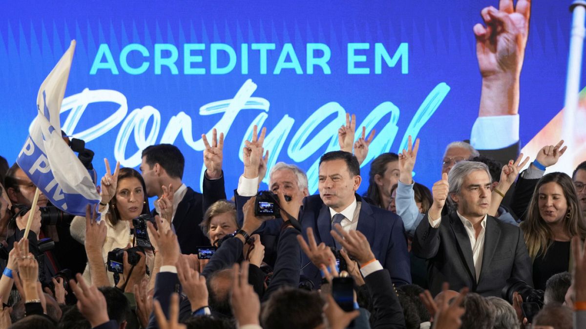Luis Montenegro, leader of the center-right Democratic Alliance, center, and his wife Carla, at left, gesture to supporters after claiming victory in Portugal