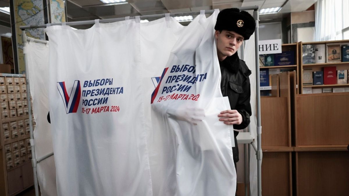 A student of the Maritime State University named after admiral Gennady Nevelskoy leaves a voting booth at a polling station during a presidential election.