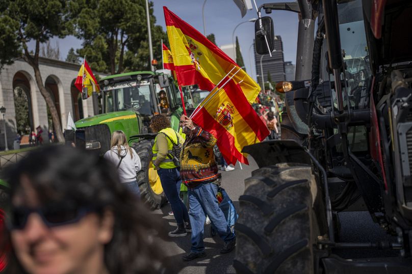 Un homme vend des drapeaux espagnols lors d'une manifestation d'agriculteurs à Madrid, en Espagne, le dimanche 17 mars 2024.