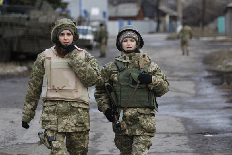 Des femmes soldats de l'armée gouvernementale ukrainienne patrouillent dans une zone du village de Debaltseve, dans la région de Donetsk, dans l'est de l'Ukraine, le mercredi 24 décembre 2014.