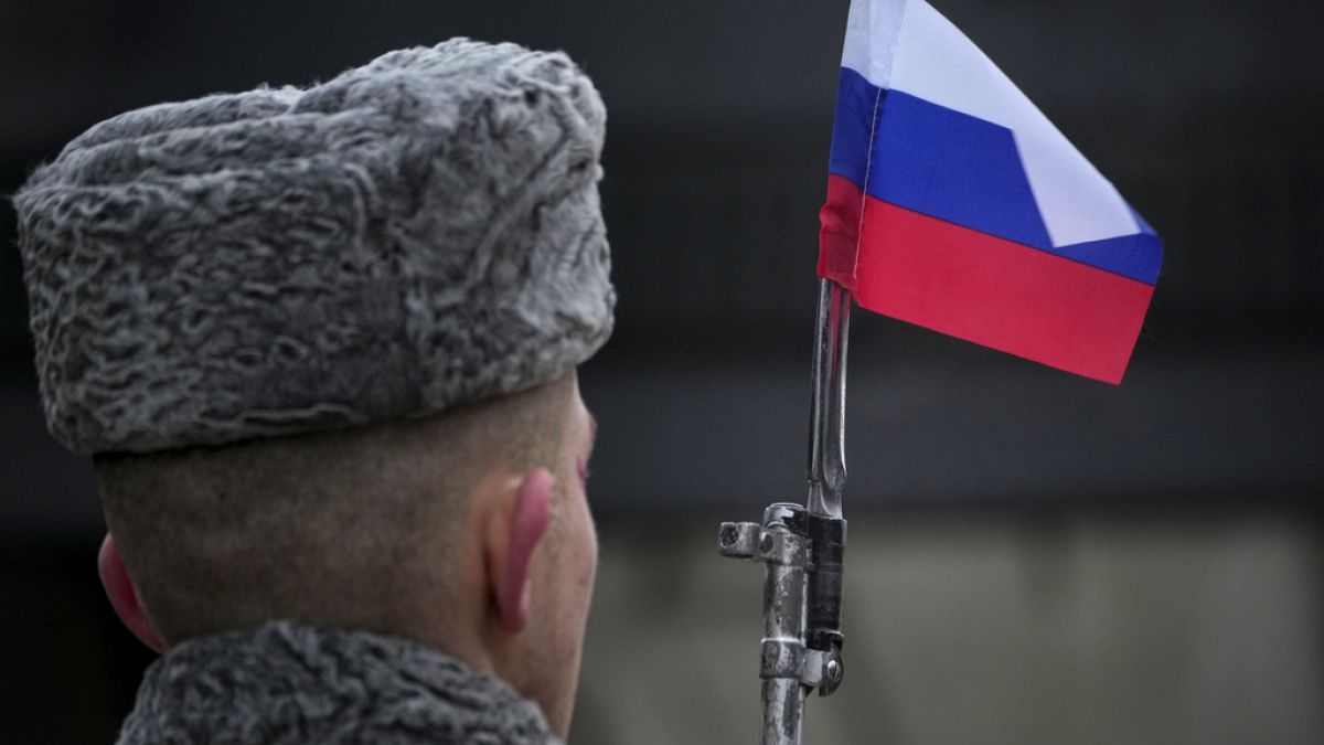 A honour guard soldier holds a rifle with a Russian flag mounted on a gun
