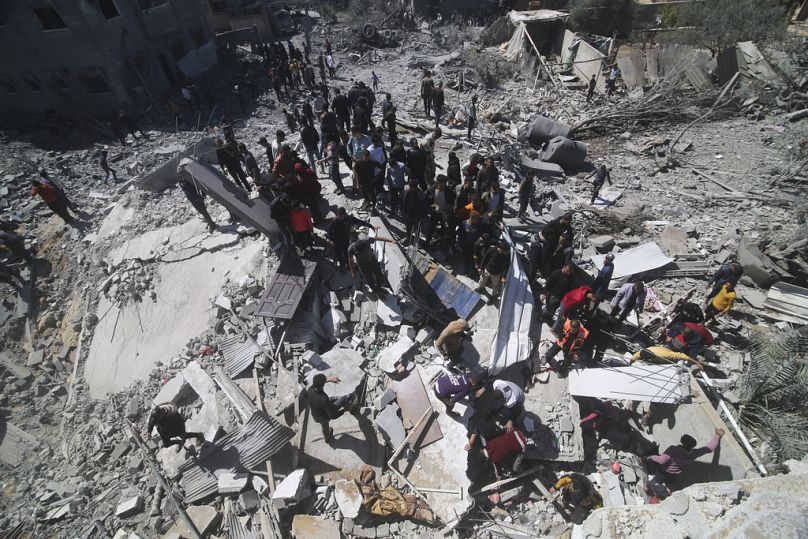 Les Alestiniens regardent un immeuble résidentiel détruit lors d'une frappe israélienne à Rafah, dans la bande de Gaza
