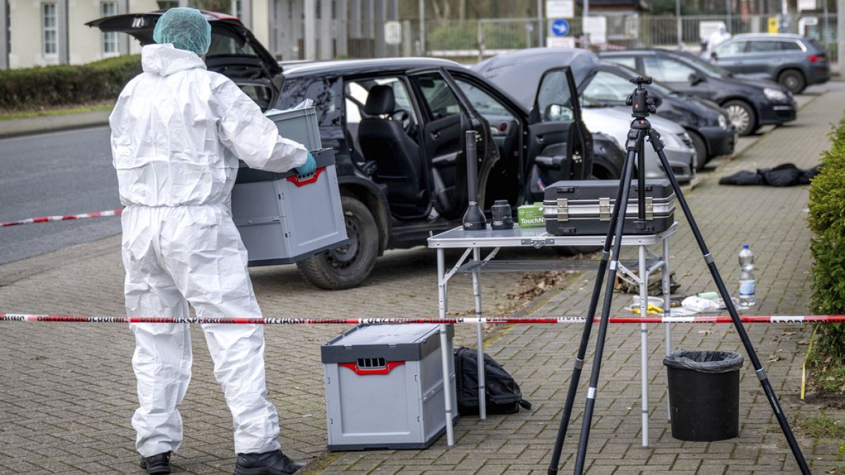 A forensics officer works near a car in front of the Von D
