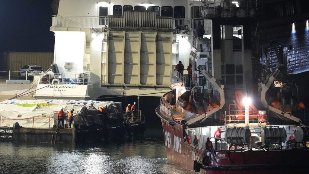 Port staffers stand on the aid platform and Open Arms aid group, as it prepares to ferry some 200 tons of rice and flour directly to Gaza